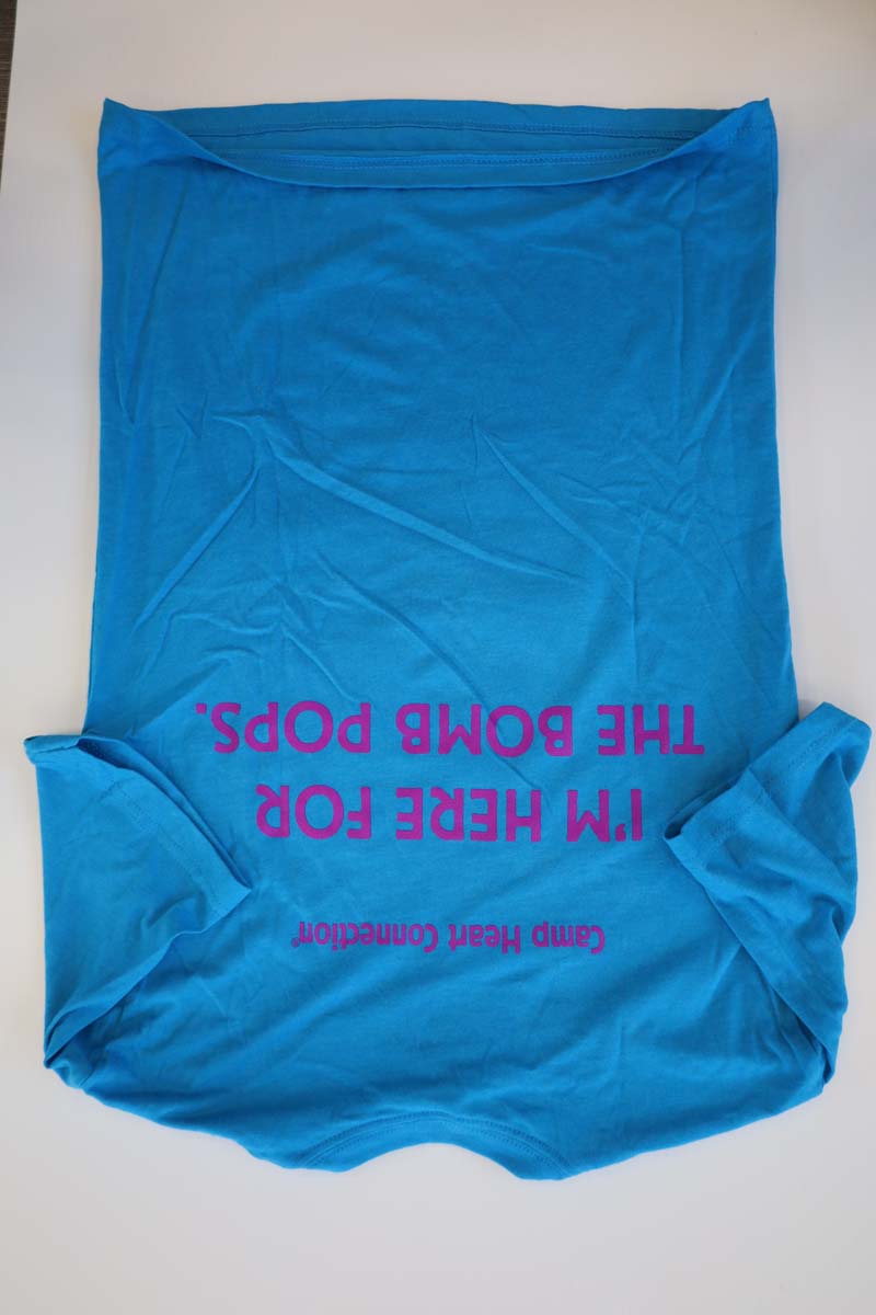 photo of back of turquoise tshirt with I'm Here for the Bomb Pops line